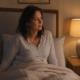 Woman sitting up in bed at night representing nocturia and nighttime urination in women over 40