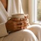 Pelvic floor daily life after 40 — woman's hands holding ceramic mug by bright window — how pelvic floor dysfunction affects confidence activity and daily life in midlife