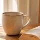 Stress and your pelvic floor after 40 — ceramic mug and open book on wooden surface — how emotional stress drives pelvic floor tension in midlife women