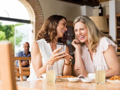 Leaking when you laugh — woman laughing with a friend at a café — a common but rarely discussed pelvic floor issue