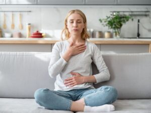 Leaking when you lift something heavy — woman practicing calm breathing with hands on chest and belly — connecting breath and core coordination to pelvic floor support