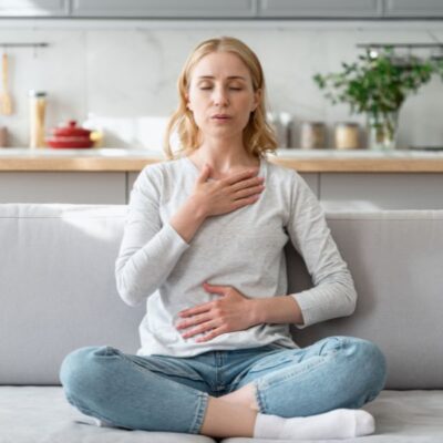 Leaking when you lift something heavy — woman practicing calm breathing with hands on chest and belly — connecting breath and core coordination to pelvic floor support