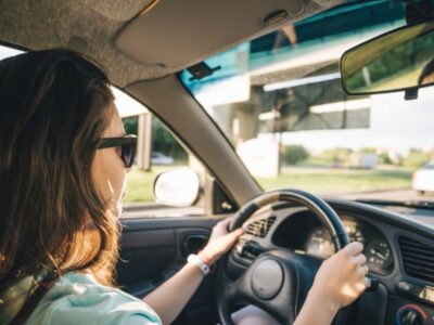 Urgency while driving — woman driving on the highway with hands on the wheel — why urgency incontinence feels worse when you're stuck in the car