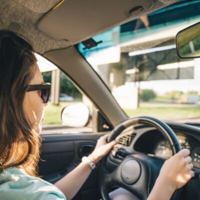 Urgency while driving — woman driving on the highway with hands on the wheel — why urgency incontinence feels worse when you're stuck in the car