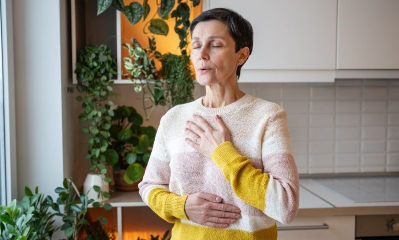How to do kegels correctly — woman over 40 breathing slowly with one hand on her chest and one on her belly.